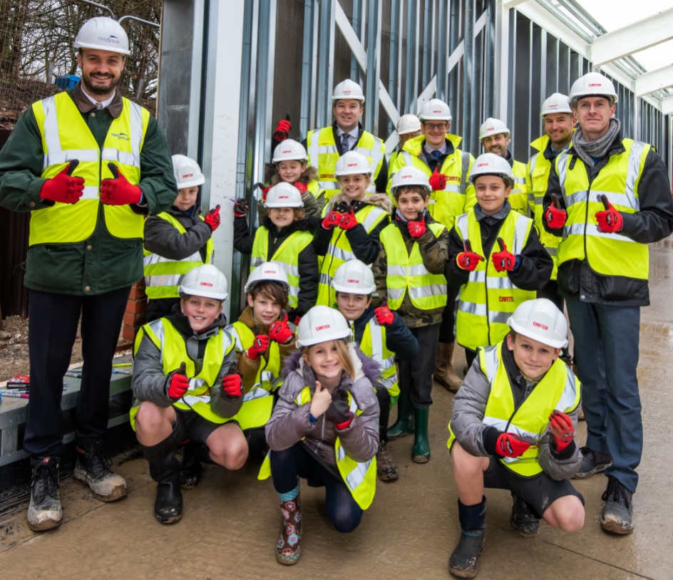 Pupils sign steel frame during new school construction work